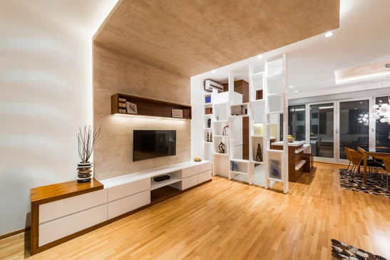 Salon moderne avec meuble TV suspendu blanc et bois, étagères géométriques blanches servant de cloison, parquet chêne massif, plafond avec faux-plafond bois