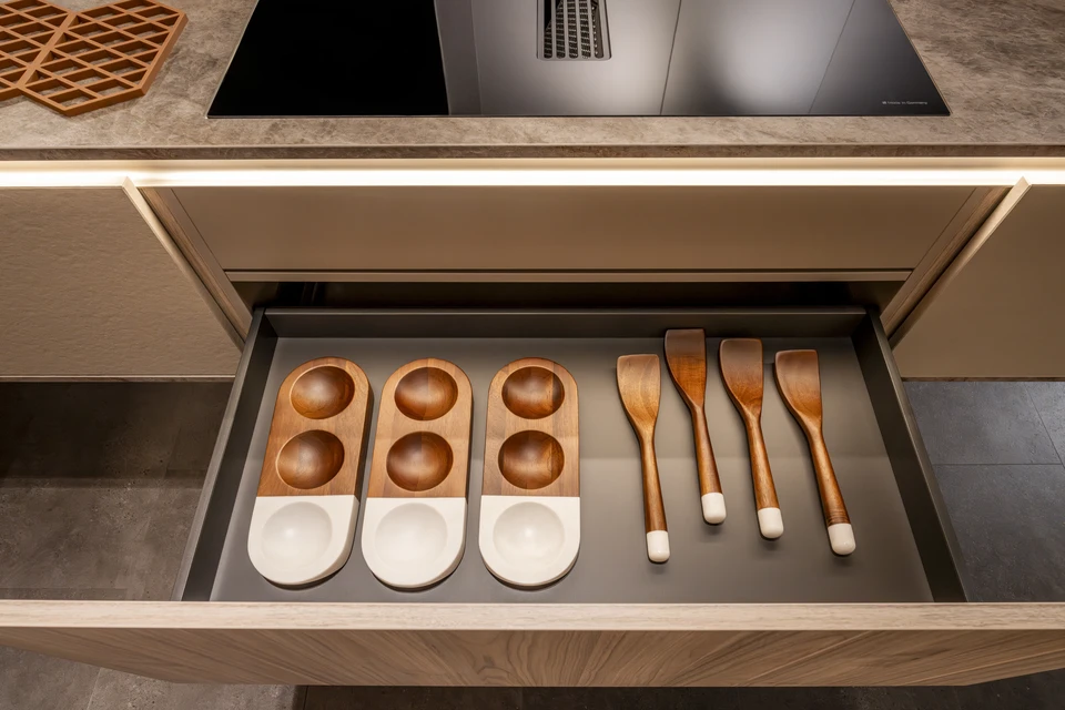 Cuisine moderne équipée avec plan de travail intégré, four encastrable avec porte vitrée, plaques de cuisson quatre feux, tiroirs de rangement, lave-vaisselle intégré