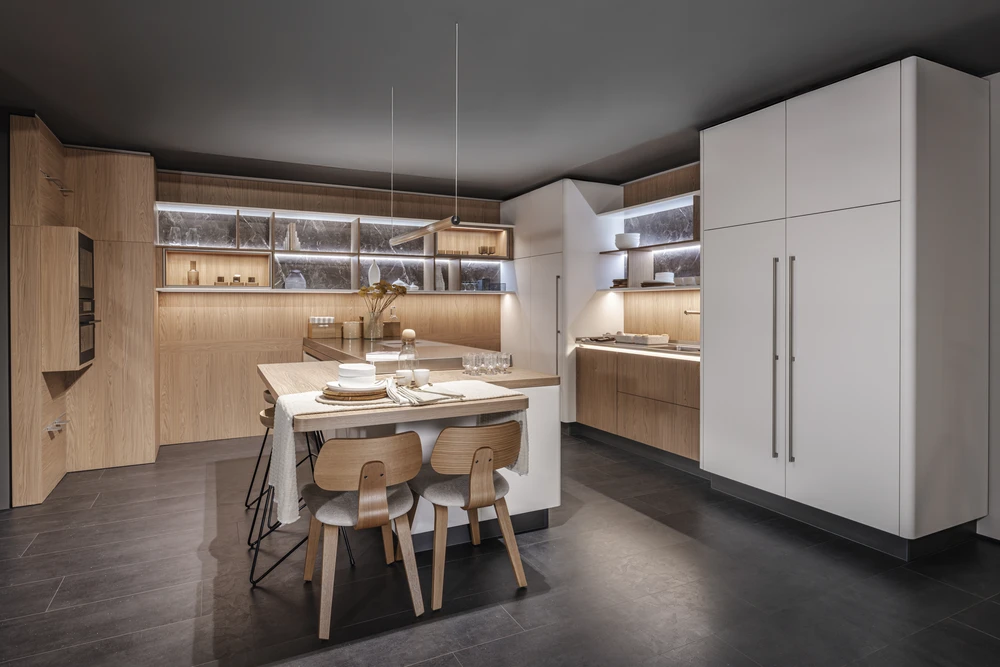 Cuisine moderne haut de gamme, plan de travail en marbre noir veiné or, crédence claire éclairée par spots encastrés sous meubles suspendus en chêne gris