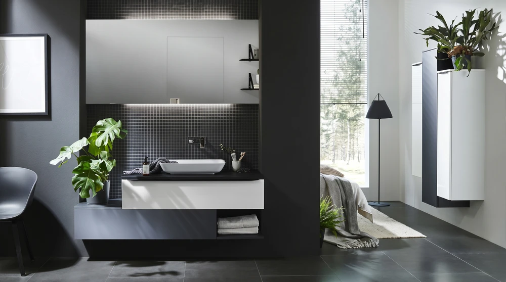 Cuisine moderne haut de gamme, plan de travail en marbre noir veiné or, crédence claire éclairée par spots encastrés sous meubles suspendus en chêne gris